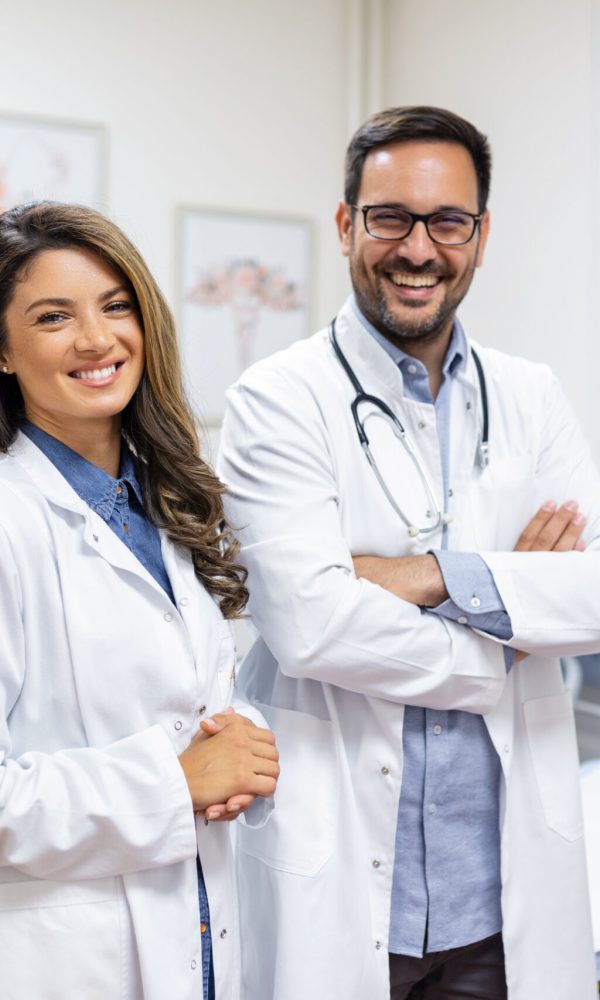 Portrait of smiling young doctors standing together. Portrait Of Medical Staff Inside Modern Hospital Smiling To Camera